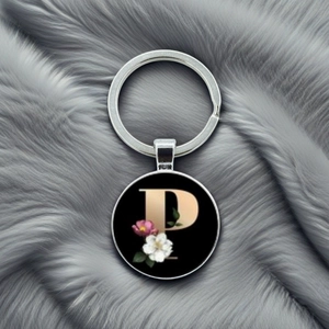 Detailed macro view of metal letter P keychain with floral patterns on grey plush surface