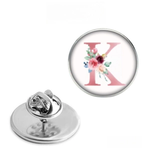 Detailed view of round metal badge with floral letter K design and butterfly clutch back
