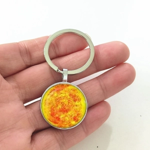 Detailed macro view of the sun-pattern glass cabochon on a polished silver metal keychain