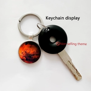 Detail view of round solar system keychain with artistic red nebula pattern on white base