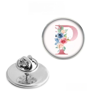 Macro view of stainless steel round brooch showing letter P and floral pattern detail