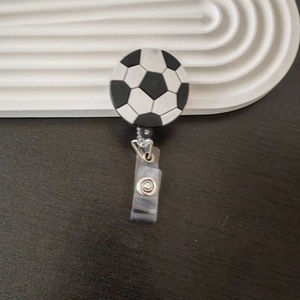 Detailed close-up of a retractable soccer ball badge holder with clear plastic clip