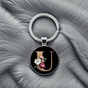 Detailed view of silver keychain with a black floral pendant featuring a golden letter U