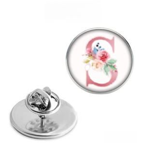 Macro detail of alphabet S brooch with pink floral design and metal butterfly clasp