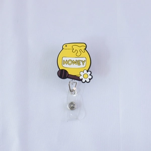 Dettaglio del porta badge in PVC a forma di vasetto di miele con testo e fiori