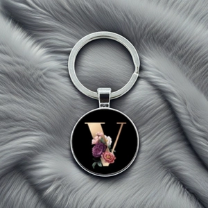 Detail of silver metal keychain with letter V pendant featuring pink and purple floral patterns