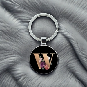 Detailed close-up of floral letter W keychain on elegant grey faux fur background