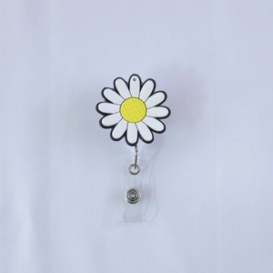 Dettaglio del porta badge in PVC a margherita con petali bianchi su tessuto bianco