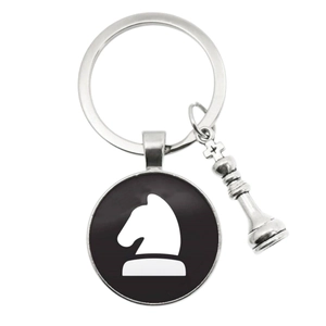 Chess themed keychain with silver knight pendant and miniature king piece charm on white background