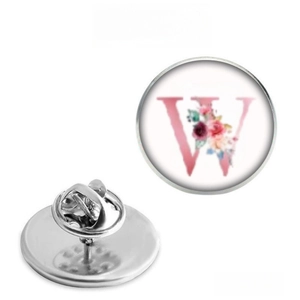 Detailed view of round metal floral brooch with letter W design and butterfly clasp
