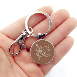 Detail of a silver keychain with religious Philippians 4:13 verse and floral pattern