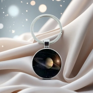 Macro shot of a silver Saturn planet pendant on soft silk background with bokeh lighting