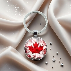 Détail du porte-clés drapeau canadien argenté avec pendentif feuille d'érable sur satin
