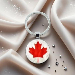 Détail d'un porte-clés Canada argenté avec feuille d'érable rouge sur du satin