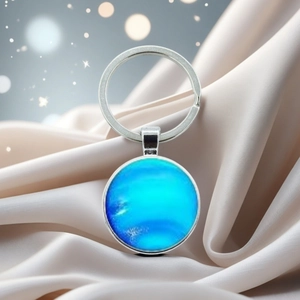 Macro view of blue planet charm keychain with silver metal on elegant silk fabric