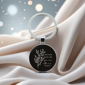 Macro detail of silver Bible verse keychain with Psalm 23:4 quote on silk background