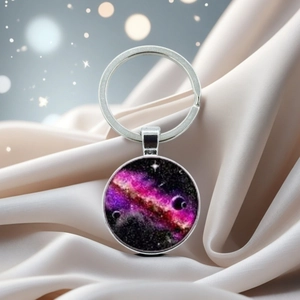 Close-up of galaxy crystal keychain on beige satin with dreamy bokeh lighting effects