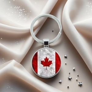Gros plan du porte-clés drapeau canadien avec feuille d'érable sur fond de satin blanc