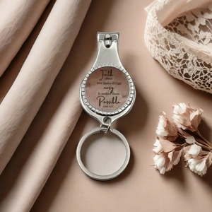 Polished metal nail clipper keychain with inspirational quote on silk background