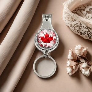 Silver metal nail clipper keychain with red maple leaf design on a silk background