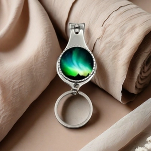 Detail of silver nail clipper keychain featuring a colorful aurora glass dome artwork