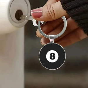 Action shot of billiard black 8 ball keychain being used to unlock a wooden door