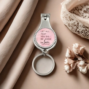 Close-up of a silver nail clipper keychain featuring a pink inspirational love quote