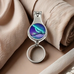 Detailed close-up of a silver nail clipper keychain featuring a scenic aurora borealis design