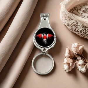 Close-up of metal nail clipper keychain with Canada maple leaf on silk and lace background