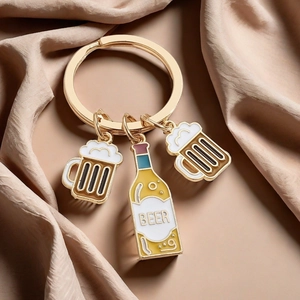 Macro shot of gold beer mug and bottle keyrings on an elegant champagne satin backdrop