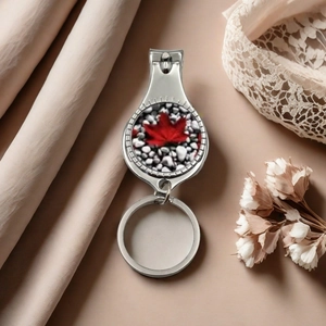 Close-up of silver metal nail clipper keychain with red maple leaf decorative emblem