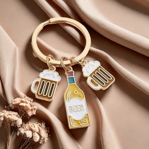 Detail of golden enamel beer bottle and mug pendants on a metal keychain set