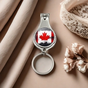 Close-up of metal nail clipper keychain with Canada flag design on fabric background