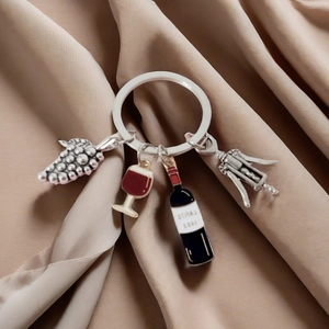 Detail of wine-themed keychain with mini bottle, glass, and opener on silk background