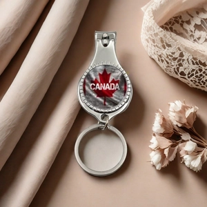Detail view of a metal Canada flag nail clipper keychain on a soft fabric background