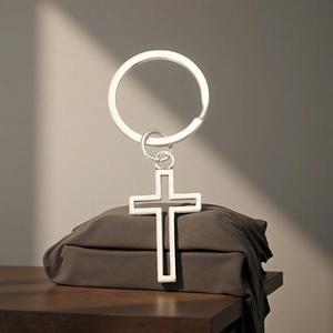 Porte-clés croix en métal argenté minimaliste avec design creux sur fond gris