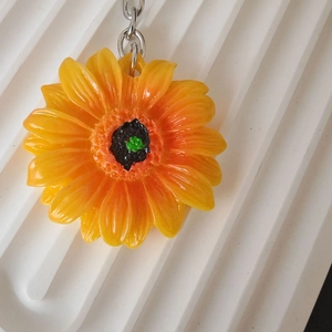 Dettaglio portachiavi a girasole con petali in resina arancione e catena in metallo argento