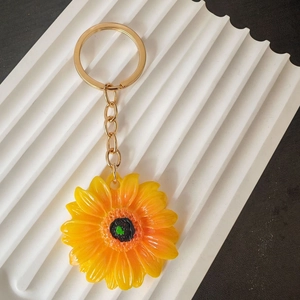 Dettaglio di un portachiavi a girasole con petali gialli e anello in metallo dorato lucido
