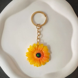 Portachiavi girasole con petali gialli sfumati posizionato su un piatto decorativo bianco