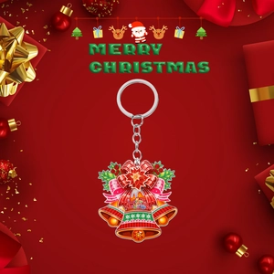 Festive 2D acrylic Christmas bell keychain with holly leaves and red ribbon on red background