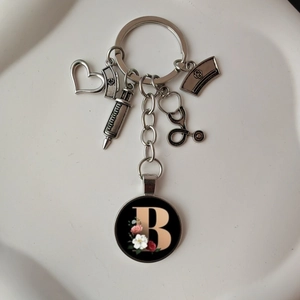 Silver metal stethoscope and heart keychain with a floral letter B charm pendant