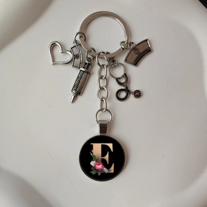 Macro shot of silver stethoscope and nurse hat charms with a floral letter E pendant