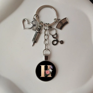 Detailed medical keychain with stethoscope, syringe, and floral letter H charm