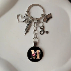 Detail view of medical keychain with heart, stethoscope charms and letter M floral disc