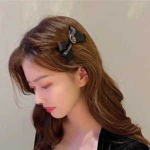 Vue détaillée d'une pince à cheveux vintage en tissu noir ornée d'une perle et de strass