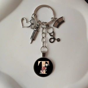 Detailed close-up of stethoscope heart keychain with floral letter T pendant and medical charms