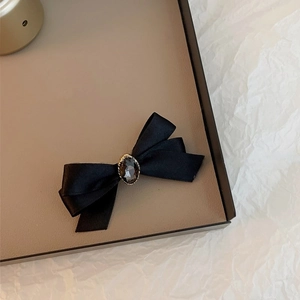 Détail d'un nœud en satin noir avec pierre précieuse centrale et support doré vintage