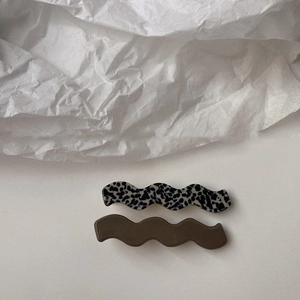 Close-up of wavy hair clips featuring black-and-white patterns and solid dark finish