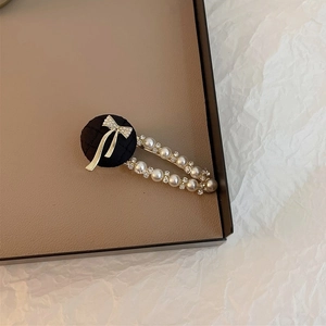 Détail d'une pince à cheveux vintage avec nœud en tissu, perles et strass sur base dorée