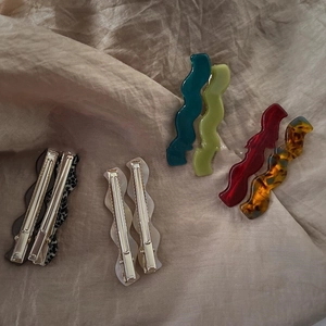 Elegant wave-shaped acetate hair clips in six vintage colors on beige fabric